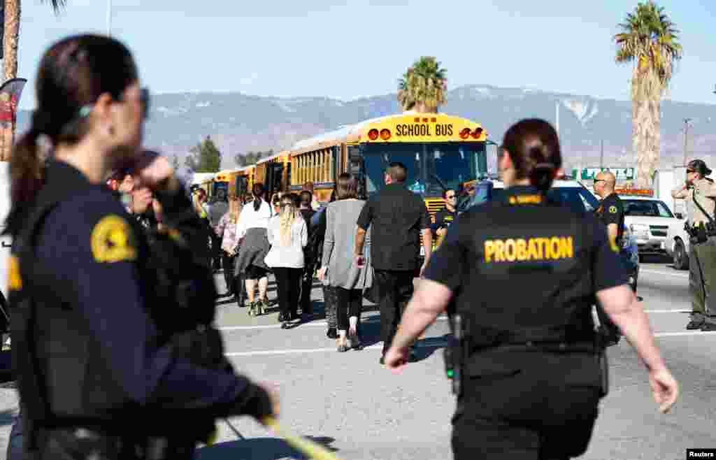 Saksi dan warga setempat diangkut ke luar lokasi penembakan saat polisi mengamankan lokasi penembakan di San Bernardino, California (2/12). (Reuters/Mario Anzuoni)