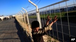 FILE - A Syrian refugee child looks over the fence at the Oncupinar camp for Syrian refugees next to the border crossing with Syria, near the town of Kilis in southeastern Turkey, March 17, 2016.