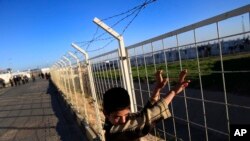 Un enfant réfugié regarde par-dessus la clôture du camp des réfugiés syriens à Oncupinar près de la frontière avec la Syrie, non loin de la ville de Kilis, Turquie, 17 mars 2016. 