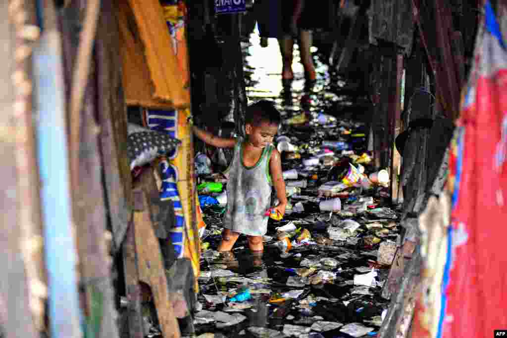 A child wades through the trash filled and polluted waters of a river beside their home in Manila, Philippines, Feb. 29, 2020.