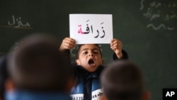 FILE - A Syrian refugee boy holds up a placard in Arabic, during class at a remedial education center run by Relief International in the Zaatari Refugee Camp, near Mafraq, Jordan, Jan. 21, 2016.