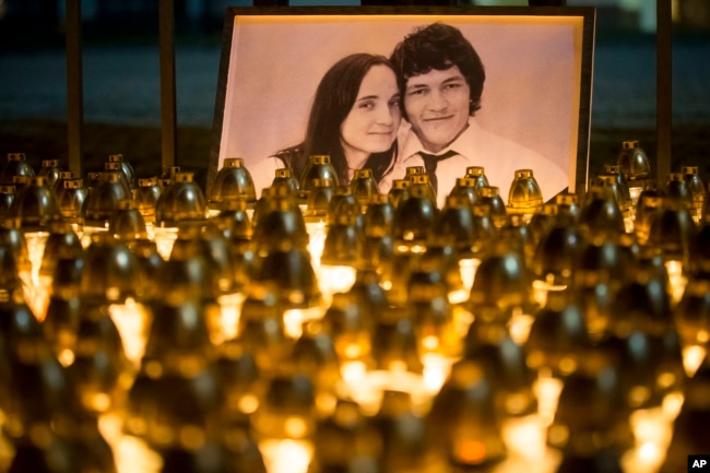 FILE - Light tributes are placed during a silent protest in memory of slain journalist Jan Kuciak and his girlfriend, Martina Kusnirova, seen in the photograph, in Bratislava, Slovakia, Feb. 28, 2018.