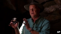 Professor Lee Berger, from the University of the Witwatersrand, holds a replica of the discovered Homo Naledi child fossil inside the Rising Star Cave in the "Cradle of Humankind" World Heritage Site near Johannesburg, Nov. 4, 2021. 