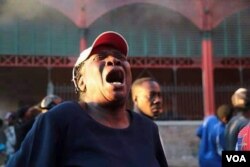 A woman sobs in front of the Iron Market as it smolders behind her in Port-au-Prince, Haiti, Feb. 13, 2018. (R.M. Givens/VOA Creole)