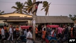 Un homme suspendu à un poteau d'électricité alors qu'il observe les partisans du candidat à la présidentielle malgache Andry Rajoelina, qui se dirige vers un rassemblement à Tuléar, le 4 novembre 2018.