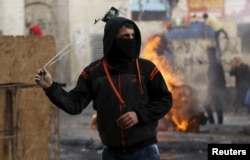 FILE - A Palestinian protester uses a sling to hurl stones at Israeli troops in Hebron, West Bank, Nov. 5, 2015.