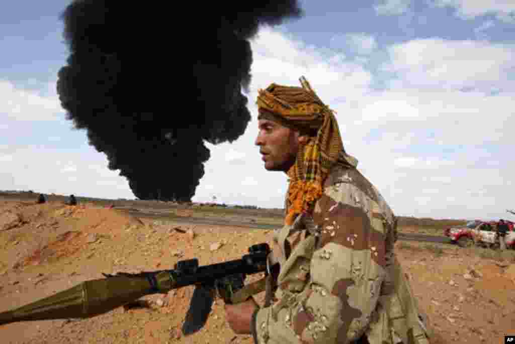 A rebel walks with his rocket propelled grenade launcher during clashes with pro-Gadhafi forces between Ras Lanuf and Bin Jawad, Mar 9, 2011
