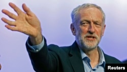The new leader of Britain's opposition Labor Party, Jeremy Corbyn, waves as he acknowledges applause before addressing the Trade Union Congress in Brighton, England, Sept. 15, 2015.