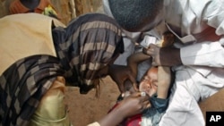 Volunteers administer a polio vaccine to a child in Kaduna, Nigeria.