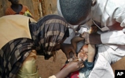 Volunteers administer polio vaccine to a child in Kaduna, Nigeria.