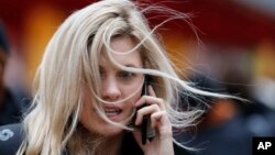 FILE - The hair of a woman is blown by the wind on a blustery day in London, Dec. 30, 2015. Heavy rains and gusty winds are causing more problems for residents in large swaths of Britain. Some flights at London's Gatwick and Heathrow airports have been diverted due to high winds battering much of Britain and western France.