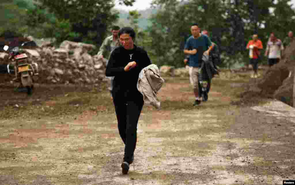 People run past a hillside alley which is at risk of landslide after an earthquake hit Ludian county of Zhaotong, Yunnan province.