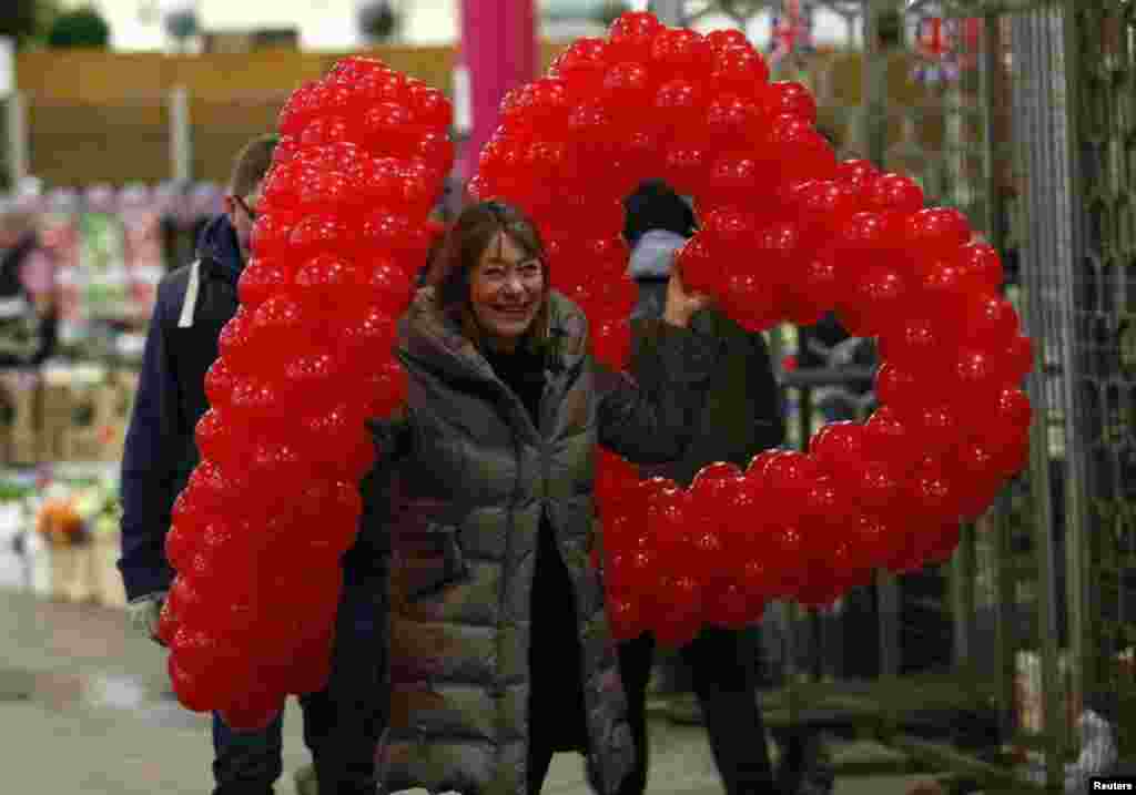 Seorang perempuan Inggris membawa balon yang berbentuk tanda &#39;hati&#39; untuk merayakan Valentine&#39;s Day di London.