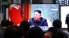 韩国首尔的火车站，人们在一个电视新闻节目中观看朝鲜领导人金正恩讲话（2021年3月25日）。