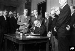 FILE - In this July 2, 1964 file photo, President Lyndon Johnson signs the Civil Rights Act in the East Room of the White House in Washington.