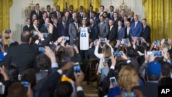 President Barack Obama holds up a Golden State Warrior basketball jersey while posing for a group photo with the team members during a ceremony where he honored the 2015 NBA Champions, in the East Room of the White House in Washington, Feb. 4, 2016.