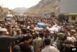 FILE - Afghan nationals prepare to cross the Torkham border post in Pakistan en route to Afghanistan, March 7, 2017.