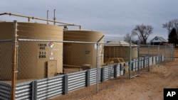 FILE - A crude oil storage tank sits behind a fence at a petroleum extraction site, in Weld County, near Mead, Colo., Feb. 13, 2017. 