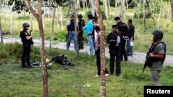 Security personnel investigate around bodies of insurgents at the site of an attack on an army base in the troubled southern province of Narathiwat, February 13, 2013. 