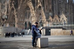 People take a selfie outside the Sagrada Familia basilica in Barcelona, Spain, Friday, March 13, 2020. The basilica closed its doors to visitors and suspend construction from Friday March 13 to prevent the spread of the new COVID-19 coronavirus