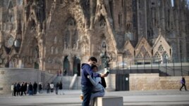 People take a selfie outside the Sagrada Familia basilica in Barcelona, Spain, Friday, March 13, 2020. The basilica closed its doors to visitors and suspend construction from Friday March 13 to prevent the spread of the new COVID-19 coronavirus