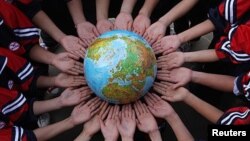 Students pose for a photo with a globe during a campaign to mark the Earth Day in a middle school in Dexing, Jiangxi province, China (file photo).