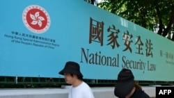 行人走过香港街头港版国安法的宣传牌。（2020年7月15日）
