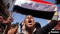 ຜູ້ປະທ້ວງ ຕໍ່ຕ້ານພວກ Houthi ຄົນນຶ່ງ ຮ້ອງໂຮ ຄຳຂວັນ ໃນຂະນະທີ່ຊູທຸງຊາດ ຂອງເຢເມັນຂຶ້ນ ທີ່ມີຄຳຂວັນວ່າ "Neither death nor humiliation" ໃນລະຫວ່າງ ການເດີນຂະບວນ ໃນເມືອງ Taiz ຢູ່ທາງພາກຕາເວັນຕົກສຽງໃຕ້ ຂອງເຢເມັນ, ວັນທີ 9 ກຸມພາ 2015. 