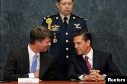 FILE - Mexico's President Enrique Pena Nieto (R) chats to BMW production chief Harald Krueger (L) during the announcement of the new BMW factory in Mexico, in Mexico City, July 3, 2014.