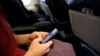 ARSIP – Seorang penumpang pesawat tampak memeriksa telepon selularnya sebelum tinggal landas dari Boston (foto: AP Photo/Matt Slocum, Arsip).