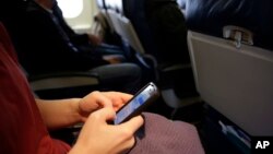 A plane passenger checks her cell phone before a flight in Boston, Oct. 31, 2013.