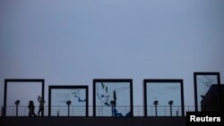 A tourist looks toward the north through a binoculars as another takes pictures at Imjingak Pavilion near the demilitarized zone (DMZ), which separates the two Koreas, in Paju, north of Seoul, March 14, 2013. 