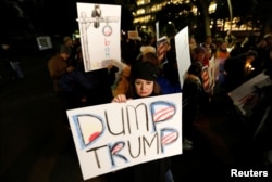 FILE - A woman holds an anti-U.S. President Donald Trump placard during a rally in Tokyo, Japan, Jan. 20, 2017.