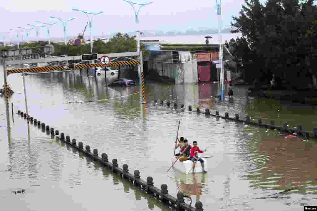 Warga mengayuh perahu buatan di jalan yang tergenang banjir akibat Topan Fitow yang melanda Rui'an, provinsi Zhejiang (7/10).