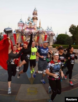 FILE - Runners in superhero outfits stream past Sleeping Beauty's Castle during the Avengers Super Heroes Half Marathon in and around the Disney Parks in Anaheim, California, Nov. 16, 2014.