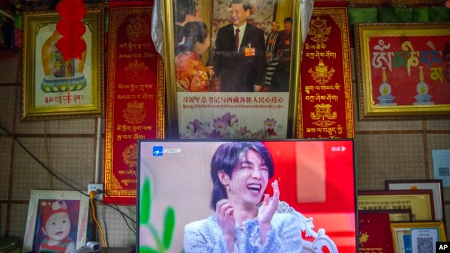 FILE - A television shows a broadcast of a Chinese talk show program as it sits beneath a photo of Chinese President Xi Jinping in a home converted into a tourist homestay in Zhaxigang village in western China's Tibet Autonomous Region, June 4, 2021.