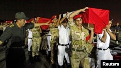 The caskets of 25 policemen killed early Monday morning near the north Sinai town of Rafah are carried after arriving at Almaza military airport in Cairo August 19, 2013. 