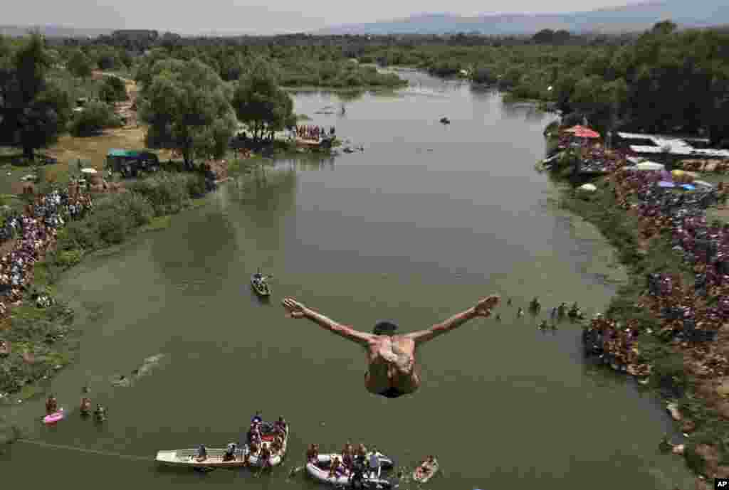 Spectators watch as a diver jumps from the Ura e Shenjte bridge during the traditional annual high diving competition, near the town of Gjakova, 100 kms south of Kosovo capital Pristina.