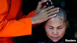 A devotee has her hair cut by a female Buddhist monk during a mass female Buddhist novice monk ordination ceremony at the Songdhammakalyani monastery, Nakhon Pathom province, Thailand, Dec. 5, 2018. 