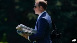 FILE - Jordan Karem, right, Deputy Assistant to the President and Director of Oval Office Operations, carries newspapers as he walks across the South Lawn of the White House in Washington, Aug. 24, 2018.
