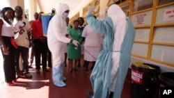 A nurse is sprayed during a tour of one of the Ebola Centers in Harare, Zimbabwe, Sept. 23, 2014.