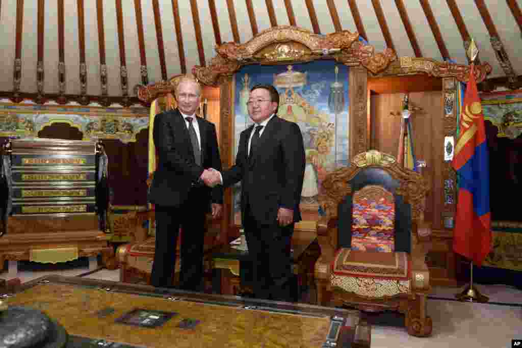 Mongolia's President Elbegdorj Tsakhia, right, and Russian President Vladimir Putin shake hands as they pose for photos at the State Palace in Ulan Bator, Mongolia, Sept. 3, 2014.
