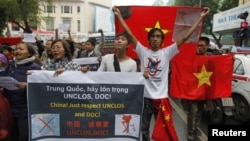 Warga Vietnam membawa bendera nasional mereka dan spanduk yang menyatakan seruan mereka saat menggelar aksi protes anti-Tiongkok di jalanan kota Hanoi, Minggu (9/12). 