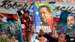 Posters during the annual May Day march in Revolution Square in Havana, Cuba show images of Fidel Castro and Venezuela's late President Hugo Chavez , May 1, 2013. 