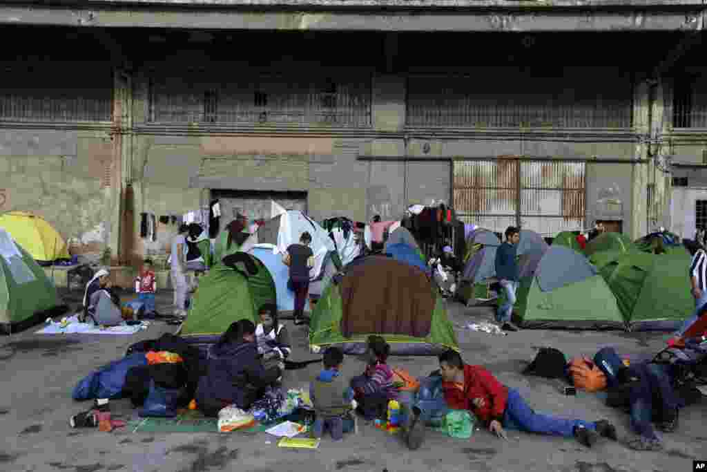 Para pengungsi dan migran duduk di luar tenda mereka di pelabuhan Piraeus, Yunani.