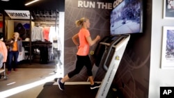 Jen Rhines, a three-time Olympic athlete, runs on a Boston Marathon treadmill that simulates the running course at RunBase, Thursday, April 16, 2015, in Boston. (AP Photo/Steven Senne)