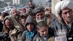 FILE - Afghan men and boys wait in line to receive their donated sacks of wheat distributed by the World Food Program in Kabul, Afghanistan, Dec. 15, 2013.