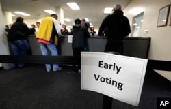 FILE - Local residents receive ballots at the Polk County Election Office on the first day of early voting in Des Moines, Iowa, Sept. 29, 2016.