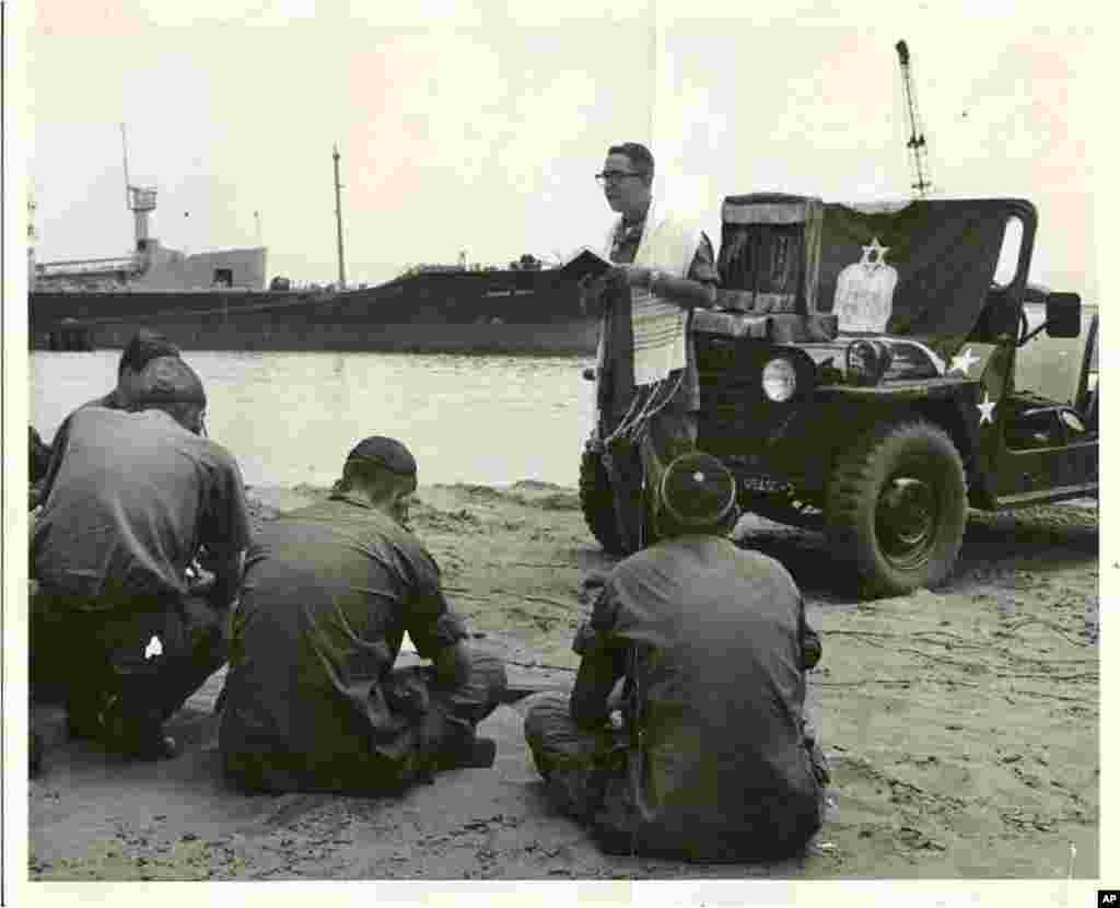 Chaplain Ernest D. Lapp (Brooklyn, NY) reads from an enlarged pulpit copy of the Jewish Prayer Book as he leads religious services on the beach at Cam Ranh Bay. (Photo: Nat'l Museum of American Jewish Military History)