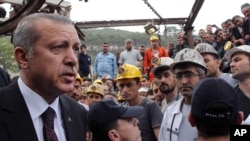 In this photo released by the Turkish Prime Minister's Press Office, Turkish Prime Minister Recep Tayyip Erdogan is surrounded by security members as he visits the coal mine in Soma, Turkey, May 14, 2014.